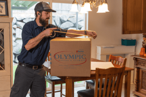 A local mover taping a moving box, looking focused.